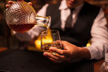 Business man bartender pours whiskey into a glass, sitting sadly in a restaurant	