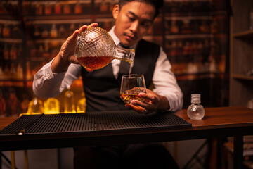 Bartender is pouring whiskey into a glass in a restaurant