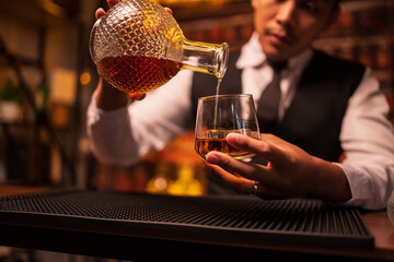 Business man bartender pours whiskey into a glass, sitting sadly in a restaurant