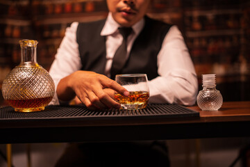 Business man bartender pours whiskey into a glass, sitting sadly in a restaurant.