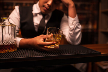 Business man bartender pours whiskey into a glass, sitting sadly in a restaurant.