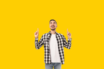 Cheerful young man points at something above him while smiling