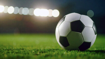 Obraz premium soccer ball on the green field at night with stadium lights background