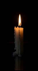 A single, burning candle casts a warm glow against a dark, reflective surface, showcasing melted wax dripping down its side.