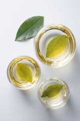 Three glass bowls containing liquid and a single leaf, arranged on a white surface, creating a clean and minimalist composition