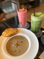 Mushroom soup with grilled bread and fresh smoothies. Appetizers for breakfast or lunch meal. Food image captures, restaurant or cafe vibe