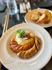 Appetizing pork sausages with mash potatoes, serve on white plate come with garlic bread. Main course for breakfast or lunch meal. Food image captures, restaurant or cafe vibe