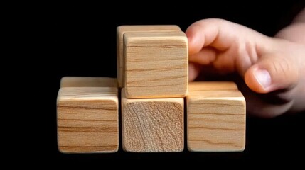 Hand Reaching for Wooden Building Blocks on Black Background in Creative Play for Children and Infants