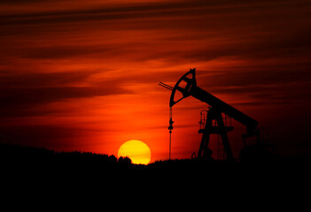 A towering oil rig silhouette against a vibrant sunset sky is a powerful symbol of the fuel and energy industry