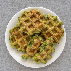 Green waffles on ceramic plate. Top view.