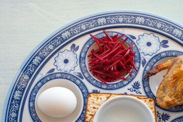 Symbolic food for Jewish holiday Pesach (Passover). Maror or bitter herbs, boiled egg, chicken bone on traditional plate for Pesach. Seder plate.