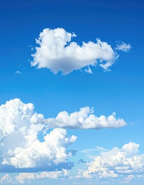 A bright, clear, vertical image features a vibrant blue sky filled with fluffy white cumulus clouds, some casting soft shadows