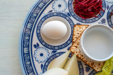Symbolic food for Jewish holiday Pesach. Boiled egg, matzah, horseradish on traditional plate. Top view.