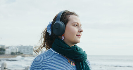 Calm, thinking and woman with headphones, beach or listening to music on vacation, happy and online. Outdoor, space and person with tech for sound, reflection and streaming playlist on holiday