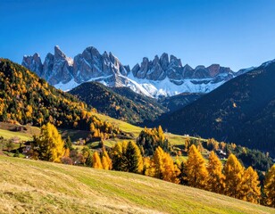 Naklejka premium A mountain range towers over a landscape of green fields, autumn-colored trees, and clear blue sky, creating a picturesque view