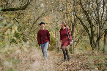 Obraz premium Authentic moment as a couple walks through a quiet autumn forest, casual outfits, natural light, candid interaction, sincere connection, unposed mood, subtle motion.