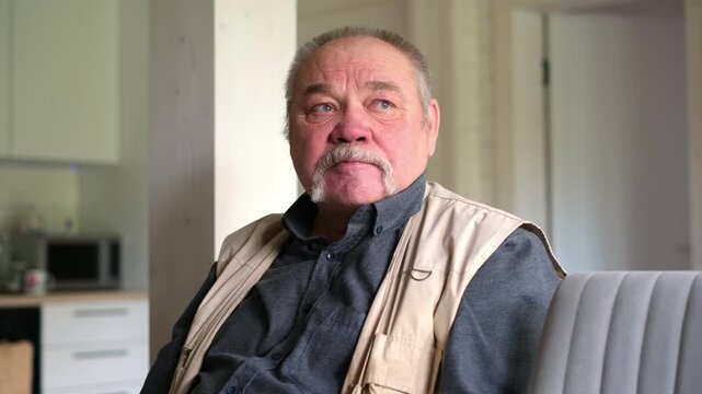 Elderly man in a living room reflects on cherished memories during Father's Day, expressing joy and nostalgia while seated comfortably, highlighting the warmth of family connections and love