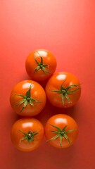 Five ripe tomatoes arranged in a loose pyramid shape on a vibrant red surface