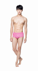 A fit, handsome Asian man in a leopard print swimsuit posing on a white background. This photo is ideal for fashion, swimwear, confidence, male beauty, and body care concepts.