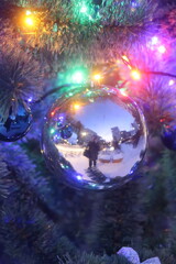 A persons reflection in a Christmas tree ornament