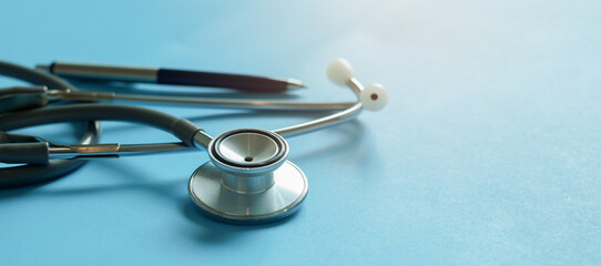 Close- up stethoscope and pen on blue background. Medical equipment for healthcare in hospital and clinic for diagnosis, treatment and health examination concept