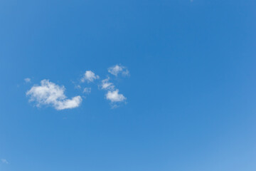Minimal blue sky with small white clouds