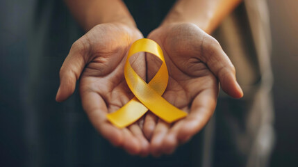 Hands holding a yellow awareness ribbon
