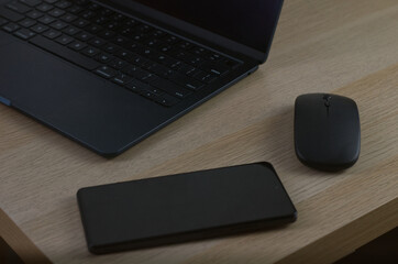 Modern Workspace with Laptop, Smartphone, and Mouse on Wooden Desk