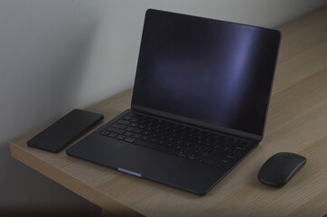 Modern Workspace with Laptop, Smartphone, and Mouse on Wooden Desk