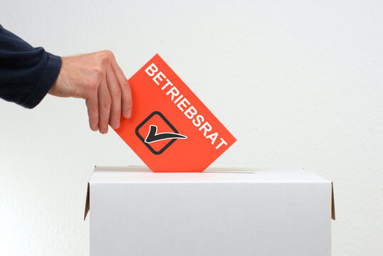 Betriebsrat - Hand wirft Stimmzettel in Wahlurne
