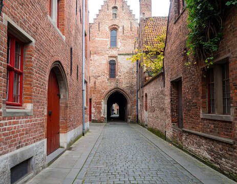Narrow cobblestone alleyway between aged brick buildings, leading to a brick archway
