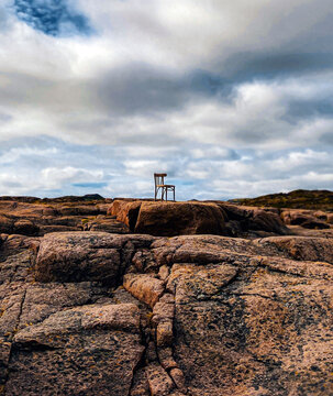 Lone White Wooden Chair Stands on Rugged Coastal Rocks. Solitude, searh concept