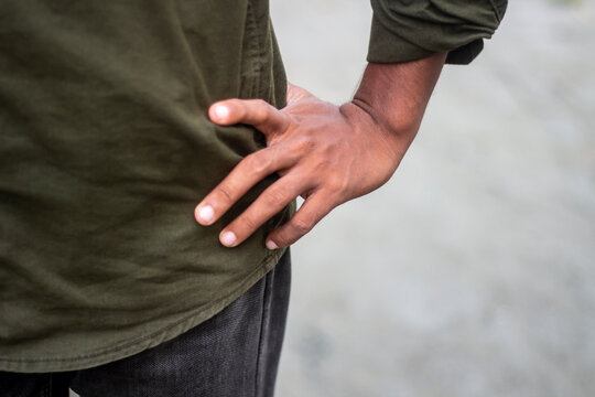 Closeup of a persons hand resting on their hip, wearing a green shirt - Powered by Adobe