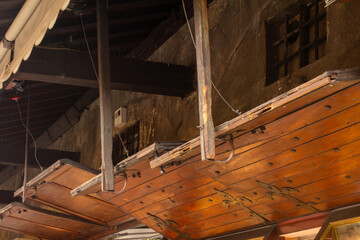 A unique close-up of the underside of a medieval, overhanging wooden balcony, highlighting its rustic craftsmanship, texture, and worn character. Ideal for historical architecture, urban exploration, 