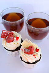 Chocolate cupcakes with cream cheese frosting with festive decorations and tea. Dessert for Valentine's Day or birthday. A wonderful festive treat for a wedding or children's party.