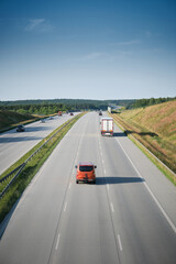 Fototapeta premium Scenic view of highway traffic with cars and trucks under clear blue sky, symbol of transport and travel.
