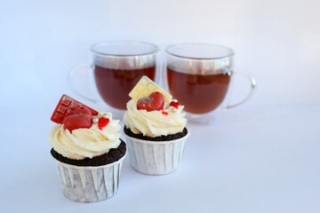 Chocolate cupcakes with cream cheese frosting with festive decorations and tea. Dessert for Valentine's Day or birthday. A wonderful festive treat for a wedding or children's party.