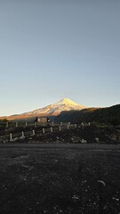 Dramatic sunrise over Volcán Villarrica in southern Chile, with warm morning light illuminating the volcanic peak and surrounding Andes landscape.