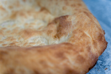 Freshly baked appetizing Uzbek flatbreads lie on table sprinkled with flour.