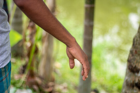 A persons arm is extended outwards with a blurred green background