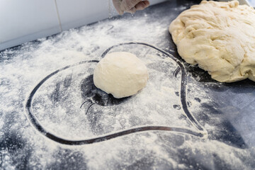A heart shape is drawn in the flour on a counter