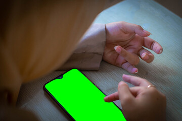 Close Up of Woman Using Smartphone with Green Screen on Wooden Table