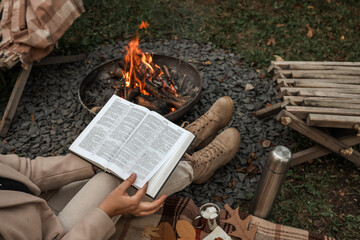 Reading by the campfire on a cozy autumn day with a warm drink and marshmallows.