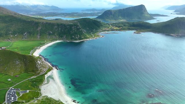Stunning aerial perspectives showcase the majestic Mannen Mountain rising above the beautiful Haukland Beach in Lofoten, Norway, capturing the vibrant coastal landscape and crystal-clear waters.