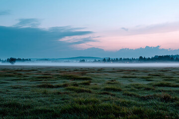 Obraz premium Mysterious mist over twilight meadow, faint light on horizon,