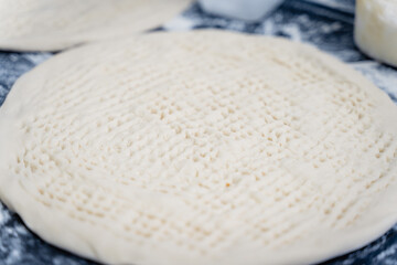 Dough for Uzbek flatbread is rolled out on table