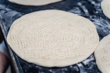 Dough for Uzbek flatbread is rolled out on table