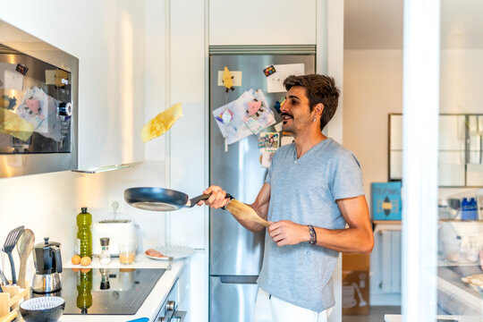 Man flipping pancake in modern kitchen