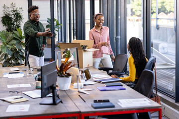 Welcoming new colleague, diverse team smiling and unpacking boxes in modern office