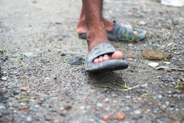 Close up of a persons foot wearing a grey sandal on a gravel path